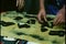 Close-up hands examining different guns laid out on cloth