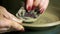 Close up hands of female potter making clay plate.