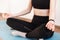 Close-up of the hands of a girl sitting on a yoga mat in a tracksuit and meditating in the lotus position. Faceless, young woman.