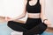 Close-up of the hands of a girl sitting on a yoga mat in a tracksuit and meditating in the lotus position. Faceless, young woman.