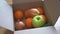 Close up of hands in gloves packing box with fruits and vegetables