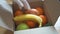 CLose up of hands in gloves packing box with fruits and vegetables