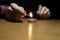 Close up hands holding a candle in the dark above the wooden surface f