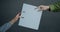 Close-up of hands holding and giving paper folder on gray background