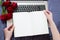 Close up - Hands holding an open notebook top view mock up. Topview on laptop keyboard and bouquet of flowers background