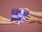 close up hands holding purple wrapped gift box. High quality photo