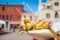 Close up of hands holding street food consisting in fried fish inside a paper cone in venice during sunny summer day