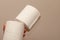 Close up of hands holding two toilet paper rolls on neutral background. Shortage and stockpile concept