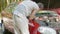 Close-up of hands of inexperienced man who approaches open hood of broken car and tries to repair it on his own