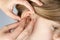 Close up of hands inserting a hearing aid in a young girl`s ear