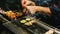 Close-up hands of Japanese Yakitori Chef grilling chicken marinated with ginger, garlic and soy sauce and cucumber.