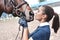 Close up hands of jockey woman hugging a horse. Young girl petting her horse in stable. Equine therapy concept. Love between
