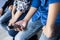 Close up of only hands and legs of teenager sitting on a wall and using smart phones and spending time with friends.