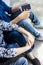 Close up of only hands and legs of teenager sitting on a wall and using smart phones and spending time with friends.