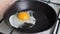 Close up of hands making fried eggs in black frying pan. Breakfast concept. Broken egg falls into the frying pan