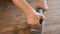 Close up hands of male, carpenter holding grinder and smoothing wood plank.