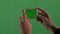 Close-up of the hands of a man with a gadget on a green background. The guy takes pictures or shoots video on a mobile