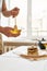 Close up of hands of man holding dipper in a bowl with honey while preparing breakfast, A stack of sweet tasty pancakes