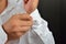 Close up of hands man how closes buttons on his white sleeve shirt at home. Clothes detail. Lights and shadows