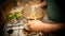 Close-up on the hands of a man shaking a casserole dish filled with ingredients, above the stove