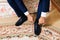 Close-up hands of a man tie laces on black shoes. A businessman in blue trousers and socks wears shoes before going to