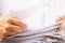 Close-up hands of a man in a white shirt searching for contract agreement documents in Stack of Group report papers clipped in