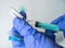 Close-up hands of a medical worker in blue gloves fill a medical syringe with the contents of an ampoule of vaccine