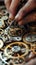 Close-up of hands meticulously assembling intricate gears and cogs of a mechanical device.