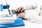 Close-up of hands middle-aged man in white shirt typing on keyboard laptop computer, holder with pencils and pens, stack of books