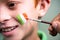 Close up of hands painting saint patricks day tricolour Irish flag on kids face during festival celebration preparations