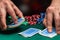 Close-up hands of a person-dealer or croupier shuffling poker cards in a poker club on background of a table, chips. Poker game or