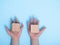 close-up of a hands placing two wooden blocks on a blue background. A child`s hand holds a cube.