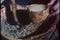 Close-up of hands pouring melted animal fat into bowl with dried meat