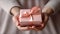 Close up of hands presenting a neatly wrapped gift box with a pink satin ribbon, embodying elegance and thoughtfulness for a