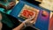 Close up of hands in protective gloves of chef spreading red caviar over cooked rice on seaweed wrap while making