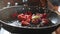 Close-up of hands puts fresh fruits in frying pan with sugar syrup, close-up