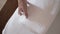 Close-up of hands putting stack of fresh white bath towels on the bed sheet. Room service maid cleaning hotel room macro