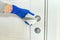 Close up of hands in rubber gloves disinfecting door handle