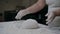 Close-up of hands of senior bakery chef applying flour to dough, kneading dough, baking bread according to traditional