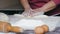 Close-up hands of senior female is cuts a dough into pieces at home kitchen.