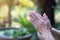 Close-up of hands senior woman joined together for pray while standing in a garden. Focus on hands wrinkled skin. Space for text.