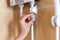 Close-up of hands setting the temperature of water in electric boiler in the shower room.
