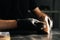 Close-up hands of shoemaker wearing black gloves swipes dust off the shoe brush in dark craft shoe shop.