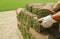 Close-up on the hands that stack rolls of grass.