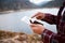 A close up of hands swiping on a tablet with lake and mountains