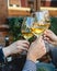 Close up on hands of unknown group of caucasian women holding glasses of white wine toasting while sitting at restaurant in day