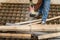 Close up on hands of unknown man holding chainsaw at warehouse or construction site sawing and cutting lumber wood