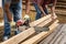 Close up on hands of unknown men holding chainsaw at warehouse or construction site sawing and cutting lumber wood