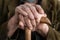 Close up on hands of unknown old caucasian man pensioner senior holding cane walking stick while sitting and waiting - real people