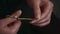 Close-up on hands of unknown woman cutting nails with manicure scissors at home. Self-care. Black background